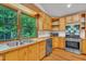 The bright kitchen features natural wood cabinets, stainless appliances, hardwood floors, and a large window overlooking the yard at 480 Big Branch Dr, Pittsboro, NC 27312