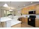 Open kitchen with warm wood cabinetry, stone countertops, and stainless steel appliances near dining at 6022 Four Townes Lane Ln, Raleigh, NC 27616