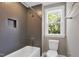 This bathroom features a white tub, shower, a gray tile wall, and a window with a view at 67 Farmstead Ct, Wendell, NC 27591