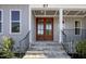 Close-up of the front entrance, featuring a wooden double door, stone steps, and a black metal railing at 67 Farmstead Ct, Wendell, NC 27591
