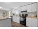 Modern kitchen with white cabinets, black appliances, and neutral countertops at 7289 Nc 561, Louisburg, NC 27549