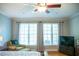 Bright bedroom with a ceiling fan, two windows with curtains, and hardwood floors at 7371 Leasburg Rd, Roxboro, NC 27574