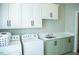 Laundry room with green and white cabinets, sink, countertop, washer, and dryer at 7371 Leasburg Rd, Roxboro, NC 27574