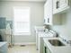 Well-lit laundry room with window, white cabinets, sink, washer, dryer, and storage at 7371 Leasburg Rd, Roxboro, NC 27574