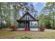 Charming cottage-style home with teal siding and red trim nestled among lush trees and landscaping at 952 Glover Rd, Dunn, NC 28334