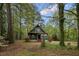 Charming cottage-style home with green siding and red trim nestled among lush trees and landscaping at 952 Glover Rd, Dunn, NC 28334