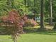 View of a two-story home with light blue siding among lush landscaping, trees, and a well-maintained lawn at 952 Glover Rd, Dunn, NC 28334