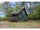 Home exterior with green siding, red trim, wooded surroundings and established lawn at 952 Glover Rd, Dunn, NC 28334