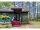 Charming green home exterior with red accents, porch and wooded surroundings at 952 Glover Rd, Dunn, NC 28334
