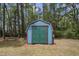 Exterior view of backyard shed with blue siding and green doors in wooded yard at 952 Glover Rd, Dunn, NC 28334