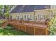 Home's back exterior showcasing a wooden deck with outdoor seating and a well-maintained lawn at 5113 Windance Pl, Holly Springs, NC 27540