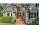 Inviting front entrance featuring stone accents, wood door, brick steps, and manicured shrubbery at 5113 Windance Pl, Holly Springs, NC 27540