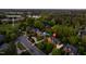 Night aerial view of a residential area with a well-lit home, tree-lined streets, and a nearby pond at 10 Twinleaf Pl, Durham, NC 27705
