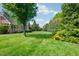Lush backyard with a sprawling green lawn, mature trees, and the back of a stately brick home at 10 Twinleaf Pl, Durham, NC 27705
