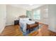 Bright bedroom featuring hardwood floors, two windows, and a bench seat in front of the bed at 10 Twinleaf Pl, Durham, NC 27705
