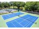 Aerial view of well-maintained tennis courts featuring vibrant blue and green surfaces, and surrounding greenery at 10 Twinleaf Pl, Durham, NC 27705