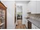 Hallway view of the butler's pantry with white cabinets, granite countertops, and a built-in wine cooler at 104 Blue Finch Ct, Youngsville, NC 27596