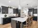 Kitchen with center island and breakfast bar with seating, black cabinets, and white backsplash at 104 Blue Finch Ct, Youngsville, NC 27596