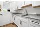 Well-lit laundry room featuring granite countertops, white cabinets, and a stainless steel sink at 104 Blue Finch Ct, Youngsville, NC 27596