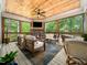 Inviting screened-in porch with wood ceiling, stone fireplace, and stylish decor with forest views at 104 Blue Finch Ct, Youngsville, NC 27596