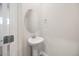 Half bath featuring a pedestal sink, oval mirror, and brushed nickel fixtures at 1048 Winding Spring Dr, Mebane, NC 27302