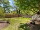 Lush backyard with mature trees, manicured lawn, wooden fence, and stairs leading up to a deck at 109 N Hassel St, Hillsborough, NC 27278