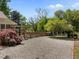 Gravel driveway leading to a charming home with mature landscaping and a wooden gate at 109 N Hassel St, Hillsborough, NC 27278