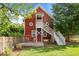 Unique red barn-style home with an elevated deck, charming white stairs, and lush green lawn at 109 N Hassel St, Hillsborough, NC 27278