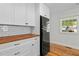 A close-up view of the kitchen with white cabinets, butcher block countertops, and black fridge at 109 N Hassel St, Hillsborough, NC 27278