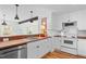 A charming kitchen with white cabinets, wood counters, brick accent wall, and stainless steel sink at 109 N Hassel St, Hillsborough, NC 27278
