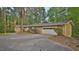 Charming brick ranch-style home with attached garage and circular driveway nestled among mature trees at 110 Omega Rd, Henderson, NC 27536