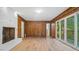 Living room with brick fireplace, wood paneling, new floors, and glass doors to the backyard at 110 Omega Rd, Henderson, NC 27536