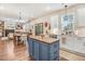 Bright kitchen with white cabinets, stainless steel appliances, and blue island open to the dining and living areas at 130 Stromness Path, Clayton, NC 27527