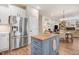 Open-concept kitchen with stainless steel refrigerator, blue island, and view into the dining and living areas at 130 Stromness Path, Clayton, NC 27527