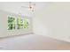 Sunlit bedroom with three large windows offering views, a ceiling fan, and neutral carpet for a cozy atmosphere at 135 Cedar Elm Rd, Durham, NC 27713