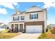 Lovely two-story home featuring brick and vinyl siding, attached two-car garage, and a cozy covered front porch at 1427 Carisbrooke Dr, Mebane, NC 27302