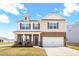 Inviting two-story home featuring brick and vinyl siding, an attached two-car garage, and a cozy front porch at 1427 Carisbrooke Dr, Mebane, NC 27302