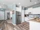 Well-lit kitchen featuring stainless steel refrigerator, white cabinets, and seamless wood-look flooring at 14315 Foxcroft Rd, Raleigh, NC 27614