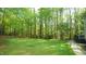 Spacious backyard surrounded by mature trees with a fire pit, seating and deck perfect for outdoor entertaining and relaxation at 1505 Sharnbrook Ct, Raleigh, NC 27614
