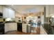 Open-concept kitchen with black countertops, white cabinets, hardwood floors, and an adjacent dining area at 1505 Sharnbrook Ct, Raleigh, NC 27614