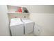 Bright laundry room featuring modern washer and dryer units, along with practical overhead shelving at 1505 Sharnbrook Ct, Raleigh, NC 27614