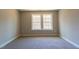 A sunlit bedroom features neutral walls, carpet and a double window overlooking trees at 213 Delma Grimes Rd, Coats, NC 27521