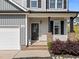 View of the front door, porch, and landscaping of a well-maintained two-story home at 220 Brisbane Dr, Zebulon, NC 27597