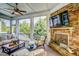 Inviting screened porch with a stone fireplace, ceiling fan, and comfortable wicker furniture at 2307 Carriage Oaks Dr, Raleigh, NC 27614