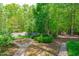 A beautiful backyard featuring a winding brick paver path through mature landscaping at 2412 Castleburg Dr, Apex, NC 27523