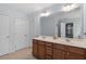 Bright bathroom featuring double sinks, vanity with wood cabinets, and ' ' and ' ' doors at 3411 Massey Pond Trl, Raleigh, NC 27616