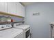 Functional laundry room features a washer, dryer, storage cabinets, and open shelving at 3411 Massey Pond Trl, Raleigh, NC 27616