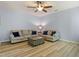 Inviting living room featuring neutral-toned sofas with blue pillows, ceiling fan, light blue walls and wood-look flooring at 3411 Massey Pond Trl, Raleigh, NC 27616