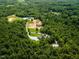 Aerial view of the estate nestled in a lush forest, featuring a long driveway and a pond at 3704 Hesters Store Rd, Hurdle Mills, NC 27541