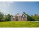 Handsome brick home with a stone facade, a metal roof, and multiple windows overlooks a lush, green lawn at 3704 Hesters Store Rd, Hurdle Mills, NC 27541